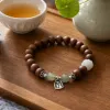 A brown beaded bracelet with green jade beads, white carved beads and silver ornaments of the character "Fu" details Picture